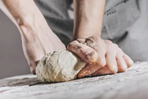 Chef making and kneading fresh dough.