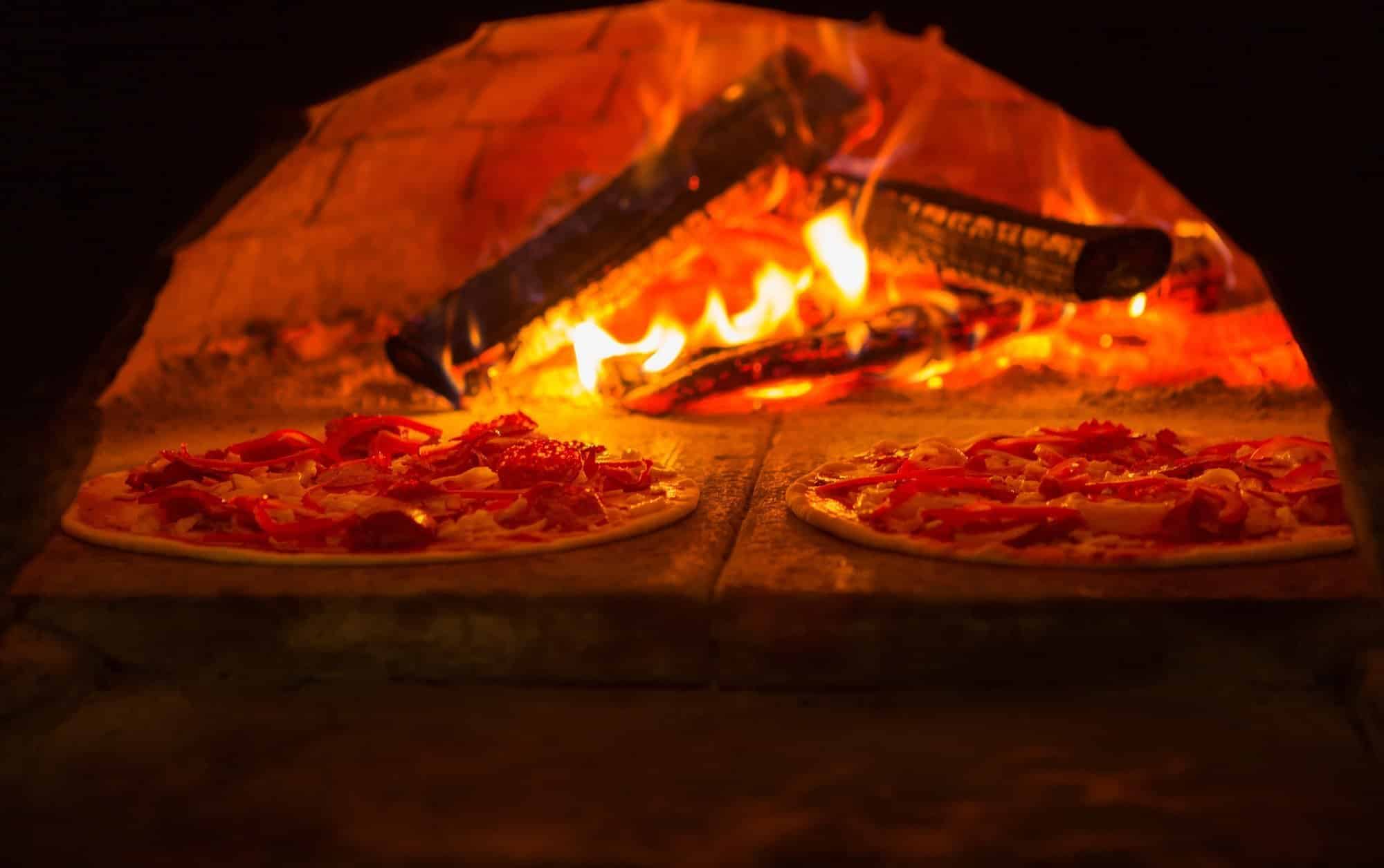 Italian pizza is cooked in wood-fired oven A traditional Italian wood-fired brick oven for cooking Neapolitan pizzas.